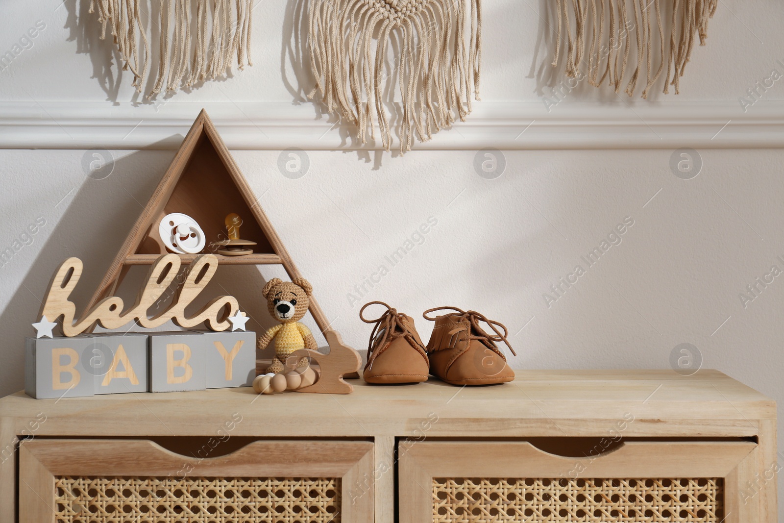 Photo of Different baby accessories and toys on wooden cabinet in child room. Interior design