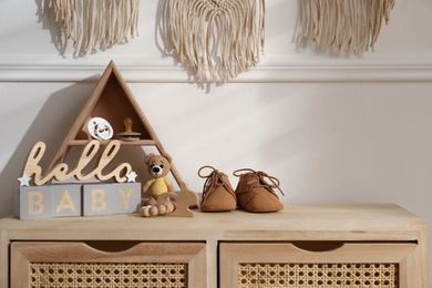 Different baby accessories and toys on wooden cabinet in child room. Interior design