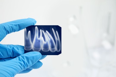 Image of Doctor holding X-ray picture of teeth indoors, closeup. Space for text