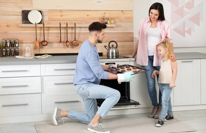 Photo of Man treating family with oven baked cookies in kitchen