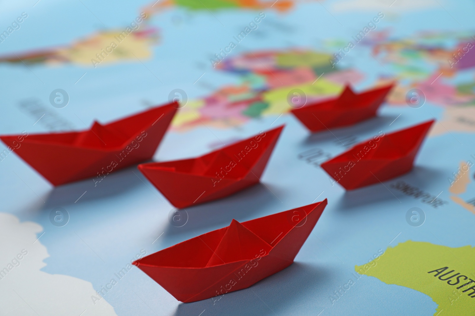 Photo of Red paper boats on world map, closeup