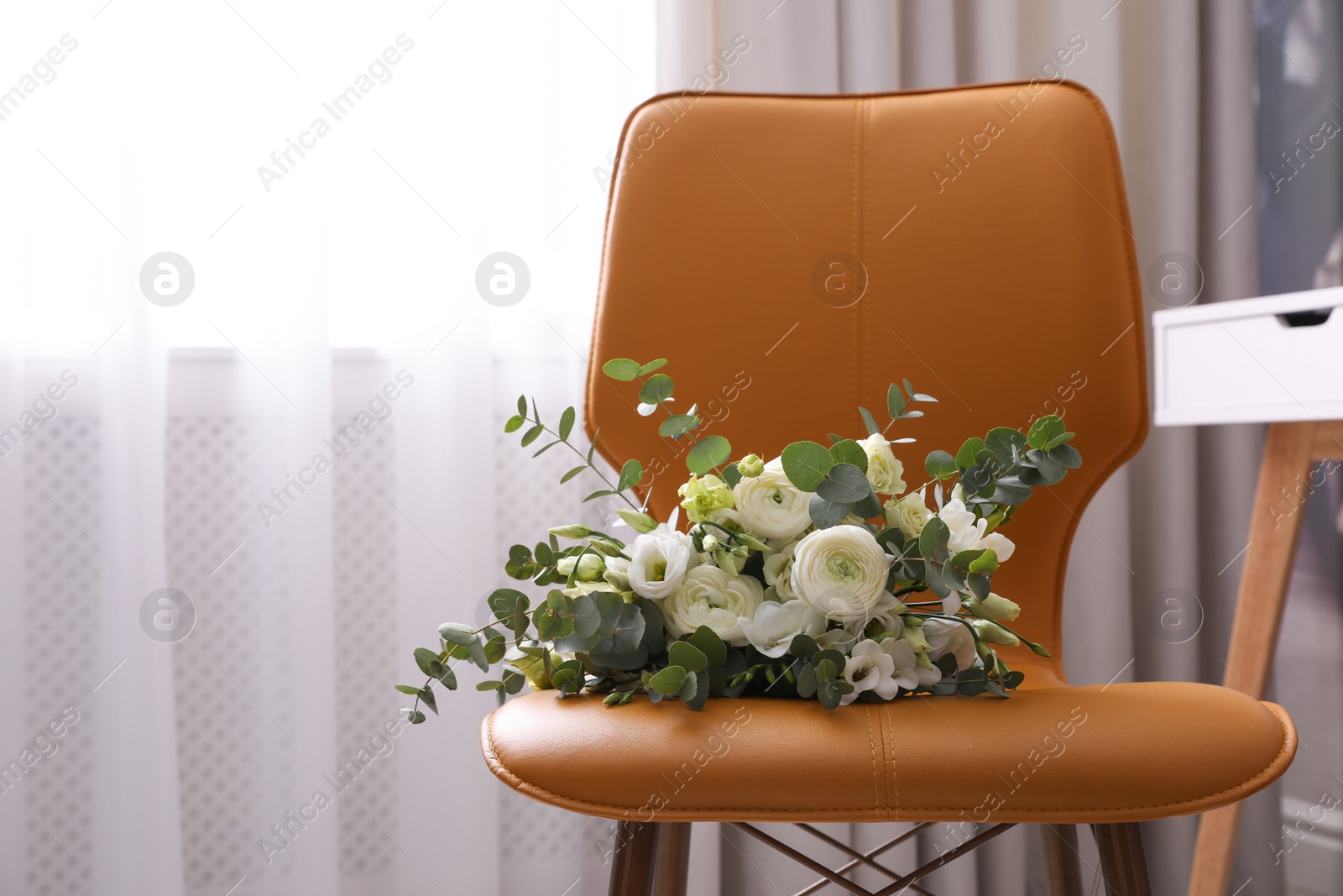 Photo of Beautiful bouquet on leather chair indoors. Interior element