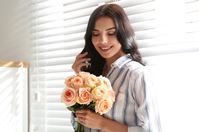 Photo of Portrait of smiling woman with beautiful bouquet near window at home