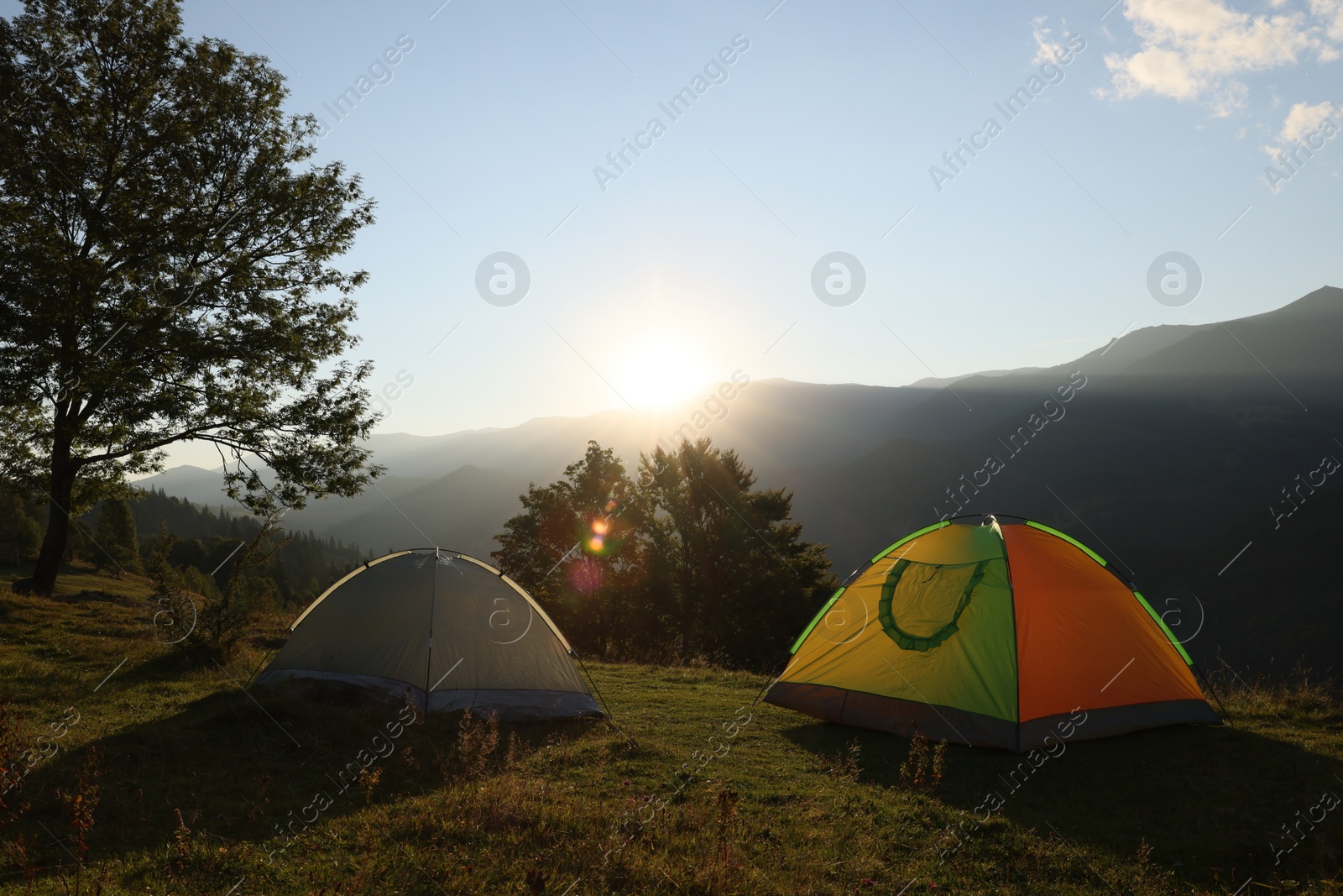 Photo of Two color camping tents on hill in mountains