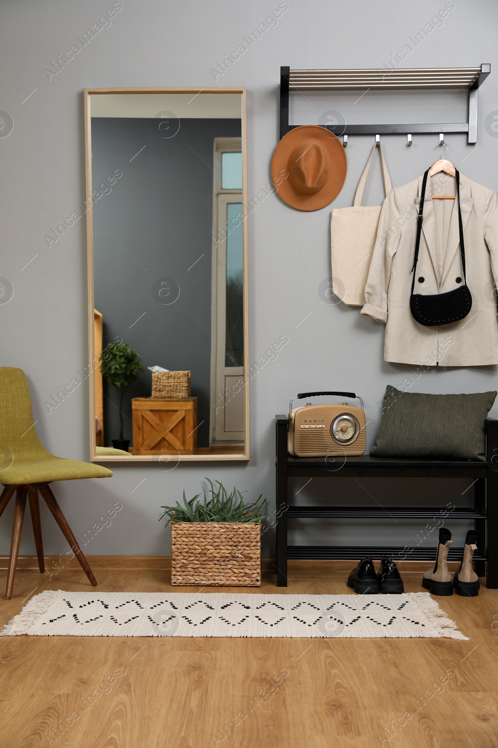 Photo of Modern hallway interior with stylish chair, shoe rack and mirror