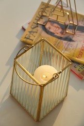 Photo of Stylish holder with burning candle, magazines and decor on table indoors