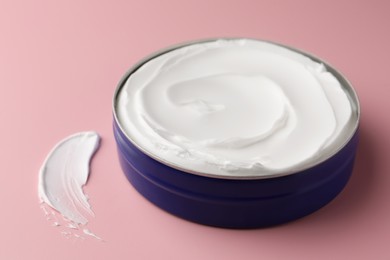 Jar of face cream and sample on pink background, closeup