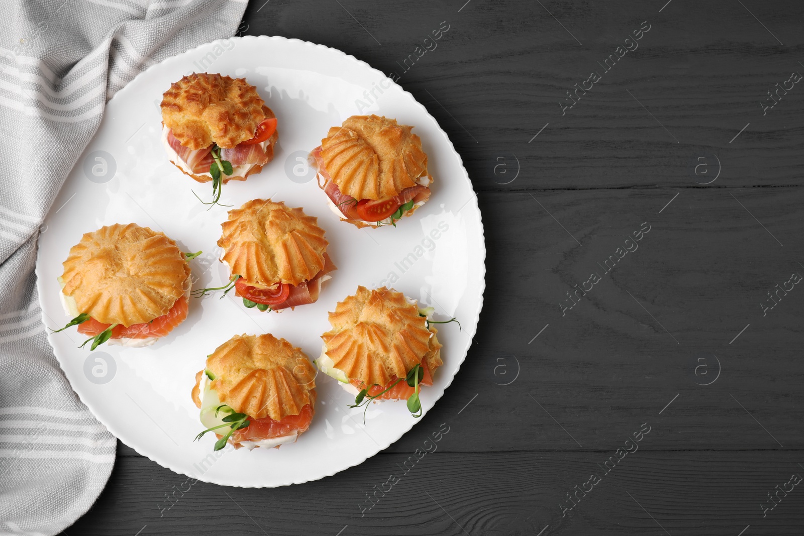 Photo of Delicious profiteroles with tasty filling on grey wooden table, top view. Space for text