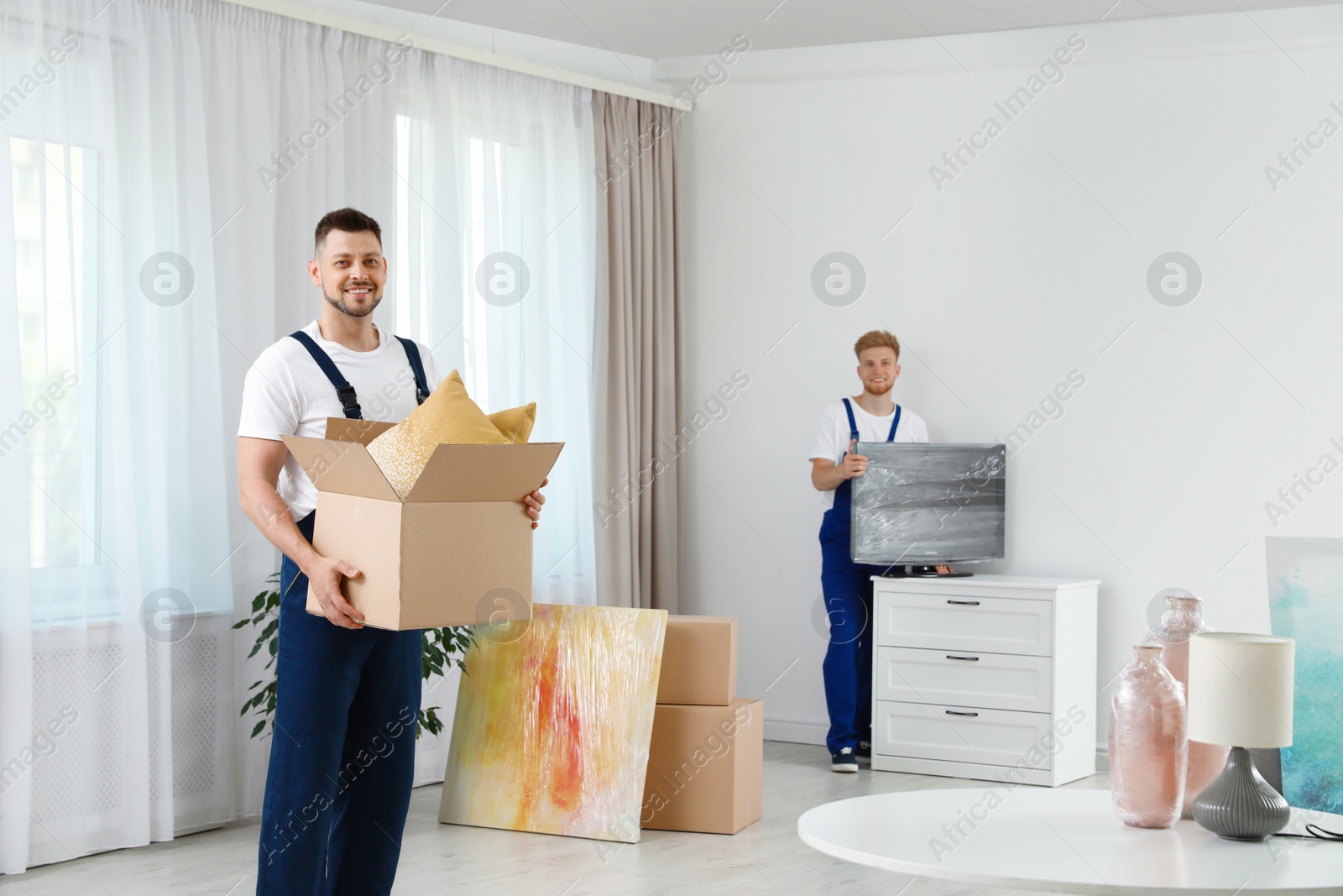 Photo of Moving service employees packaging belongings in room