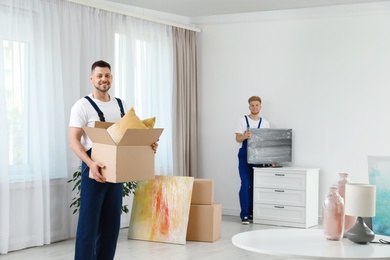 Moving service employees packaging belongings in room