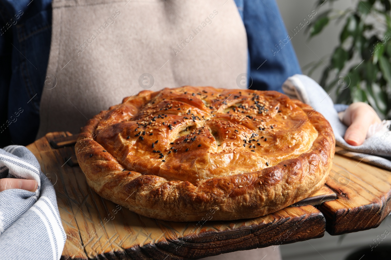 Photo of Woman holding tasty homemade pie indoors, closeup