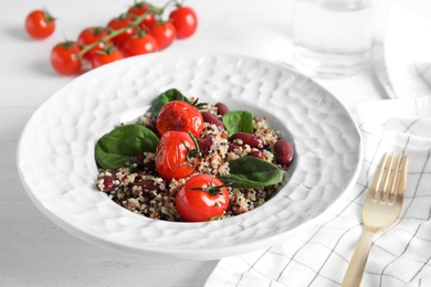 Photo of Plate with healthy quinoa salad and vegetables on table