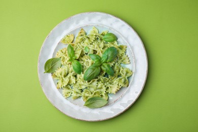 Photo of Delicious pasta with pesto sauce and basil on light green background, top view