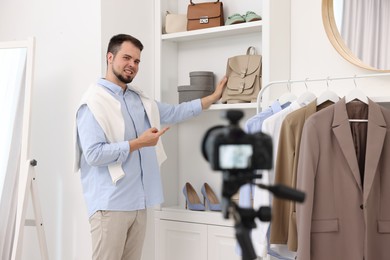 Smiling fashion blogger showing clothes while recording video at home