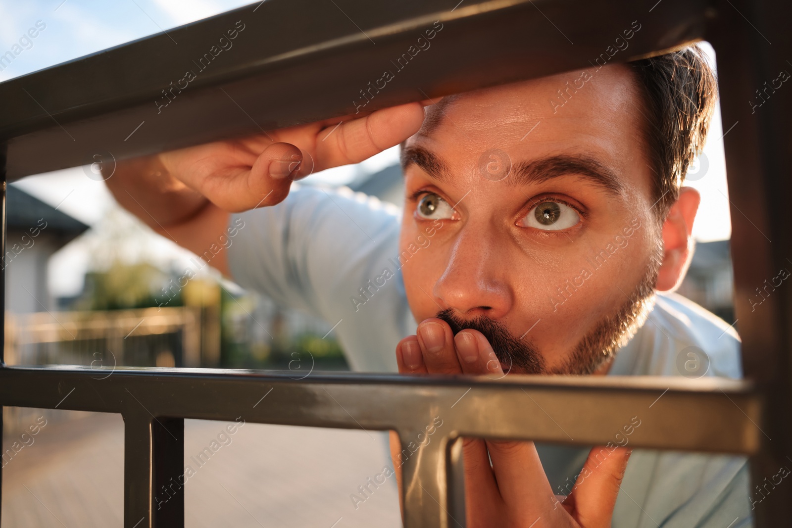 Photo of Concept of private life. Curious man spying on neighbours over fence outdoors, closeup