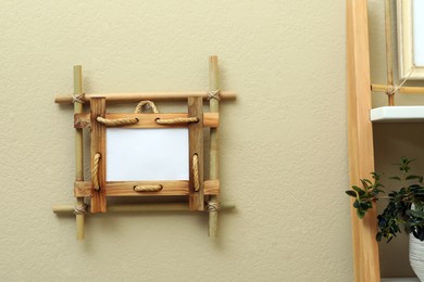 Photo of Bamboo frame on beige wall near rack