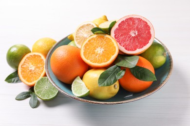 Photo of Different cut and whole citrus fruits on white wooden table