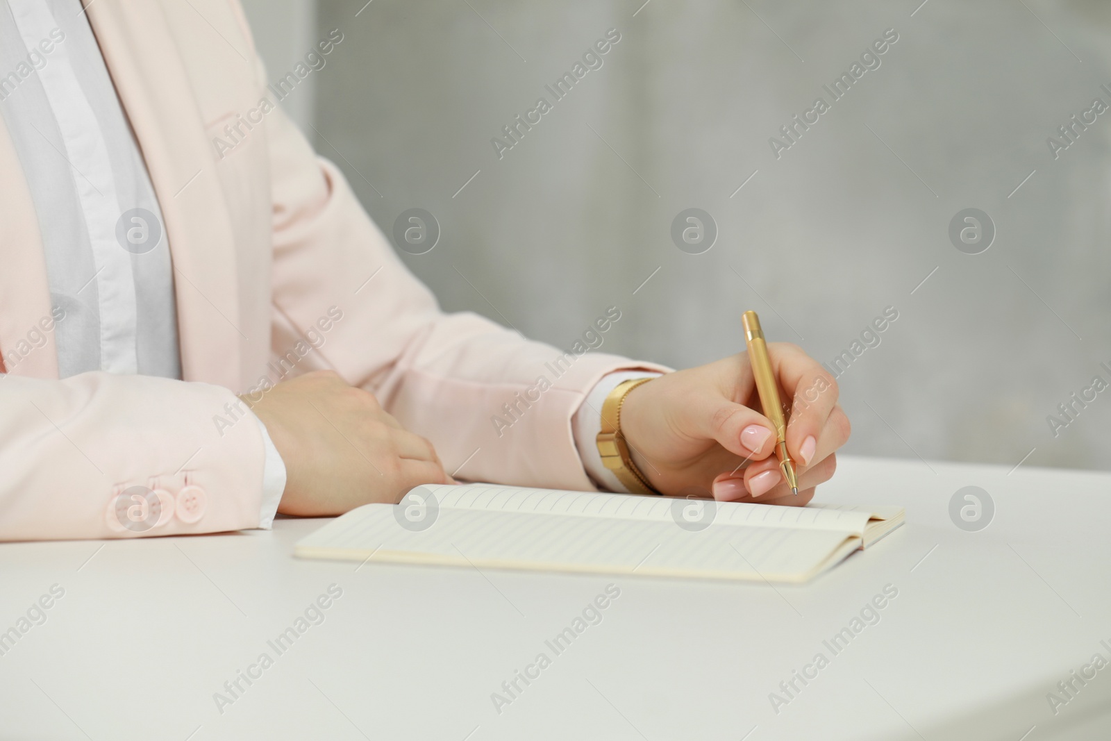 Photo of Woman writing in notebook at white table, closeup