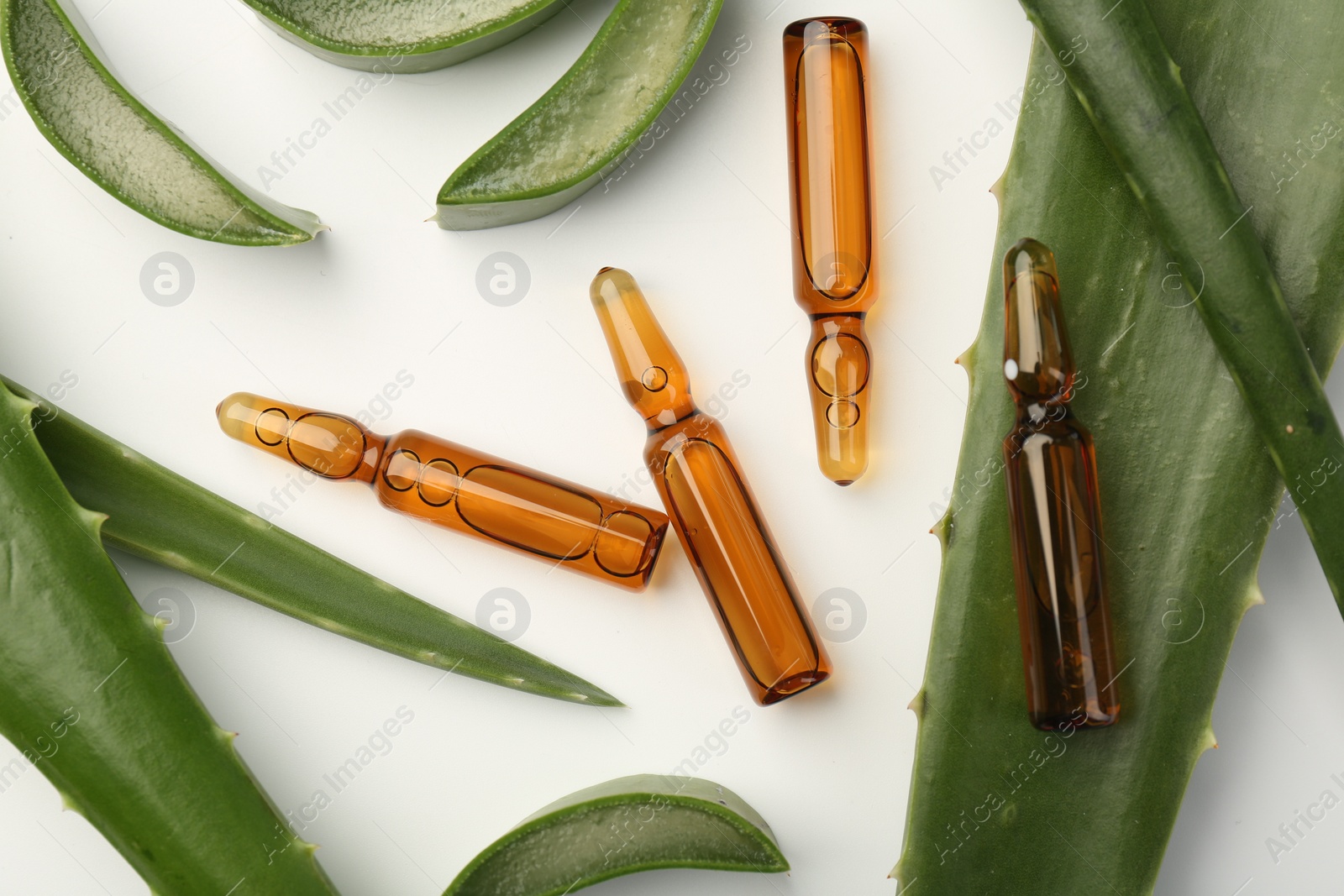 Photo of Skincare ampoules and aloe leaves on white background, flat lay