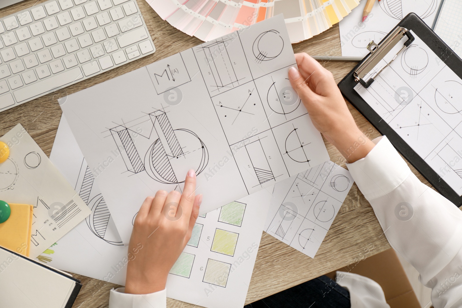 Photo of Female designer working at wooden table, top view