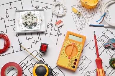 Photo of Different electrician's equipment and screwdriver on wiring diagrams, flat lay
