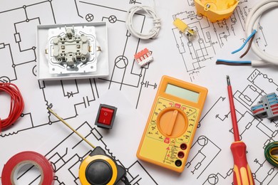 Different electrician's equipment and screwdriver on wiring diagrams, flat lay