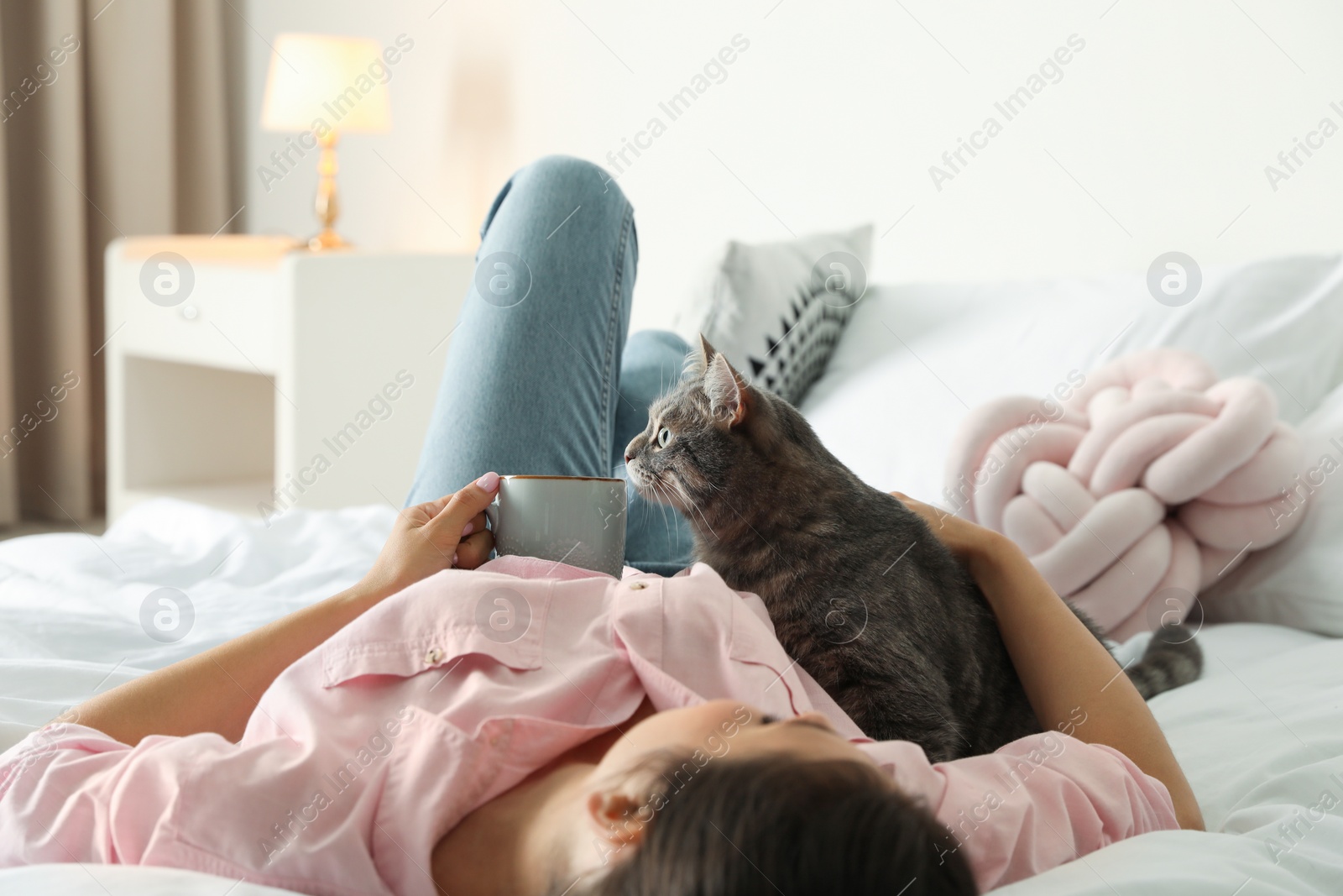 Photo of Young woman with cute cat on bed at home. Pet and owner