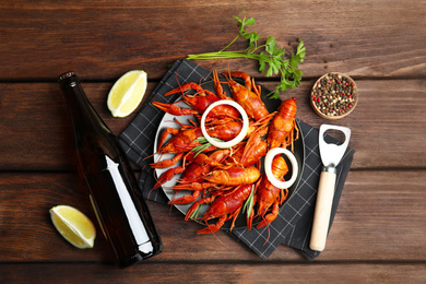 Flat lay composition with delicious red boiled crayfishes on wooden table