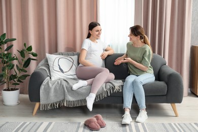 Doula working with pregnant woman on sofa at home. Preparation for child birth