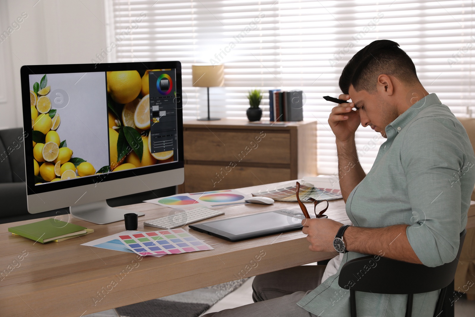 Photo of Tired retoucher at workplace with computer in office