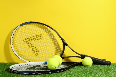 Photo of Tennis rackets and balls on green grass against yellow background. Sports equipment