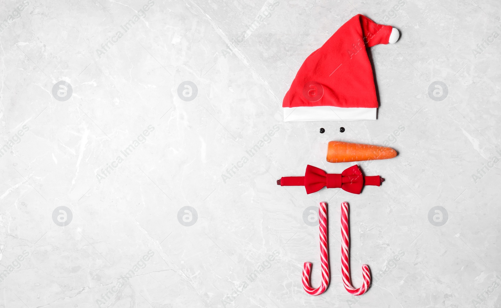 Photo of Funny snowman made with different elements on light grey marble background, flat lay. Space for text
