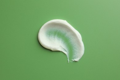 Photo of Sample of face scrub on green background, top view