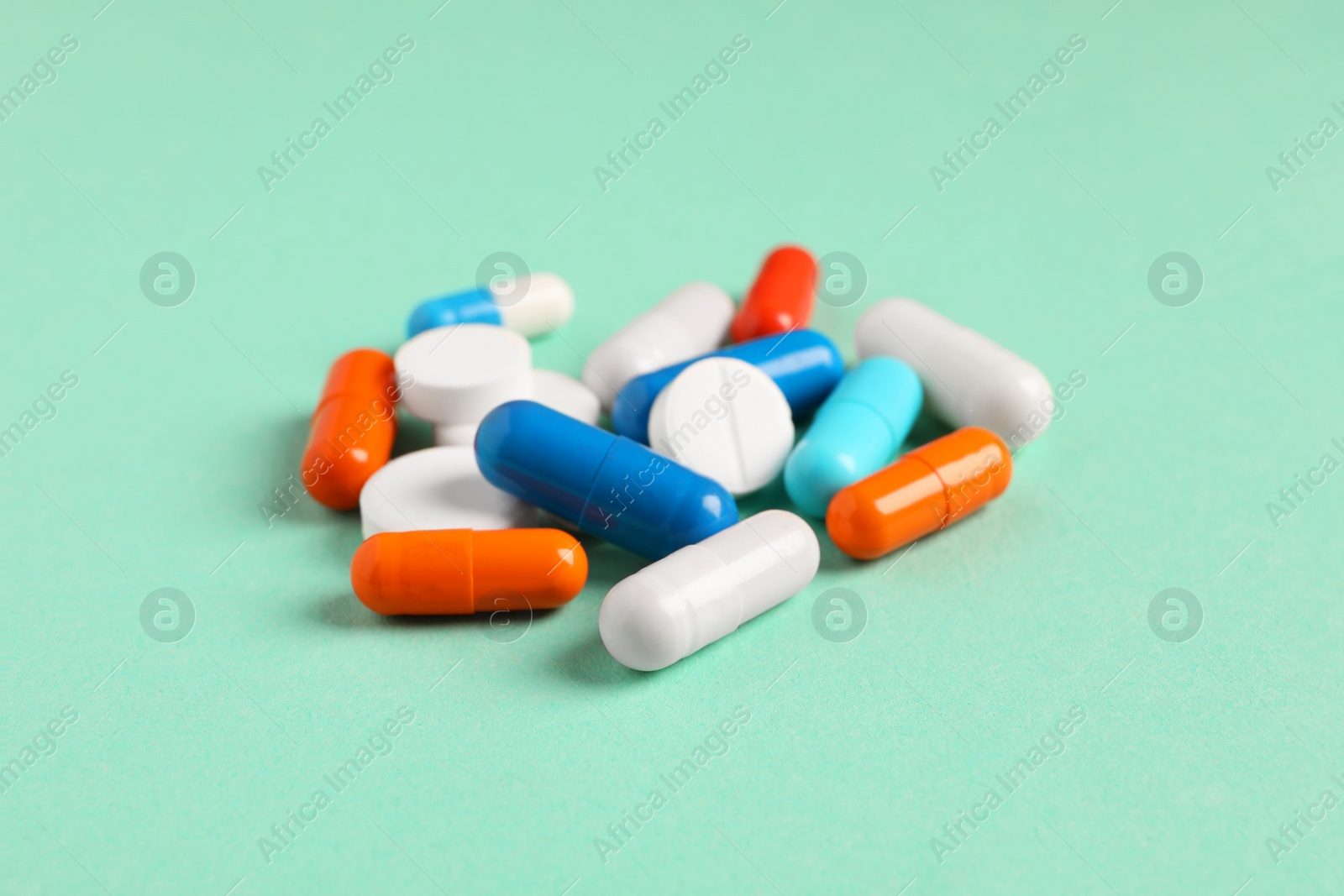 Photo of Pile of colorful pills on green background, closeup