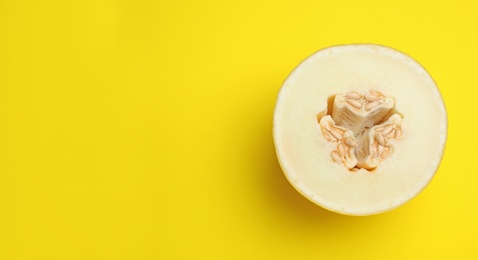 Half of ripe tasty melon on yellow background, top view. Space for text