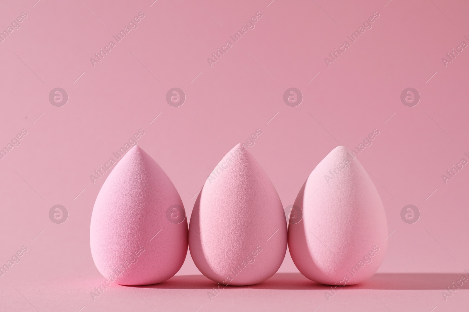 Photo of Three colorful makeup sponges on pink background