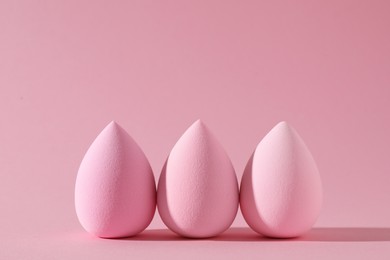 Three colorful makeup sponges on pink background