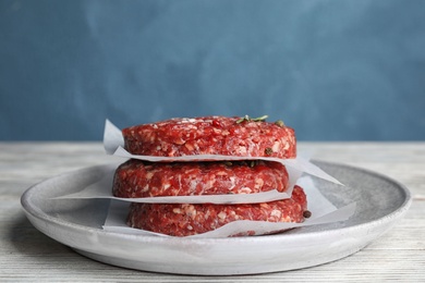 Raw meat cutlets for burger on white wooden table against blue background. Space for text