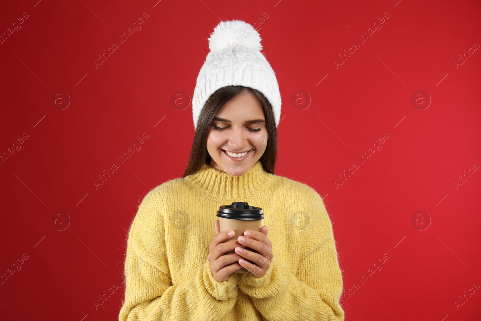 Photo of Happy beautiful woman with paper cup of mulled wine on red background