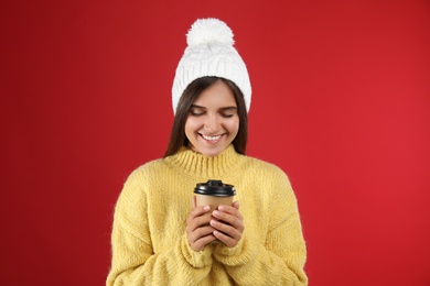 Photo of Happy beautiful woman with paper cup of mulled wine on red background