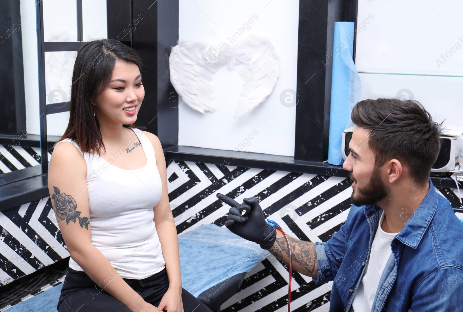Photo of Professional tattoo artist with client in salon