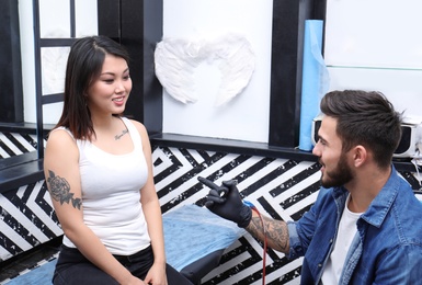 Photo of Professional tattoo artist with client in salon