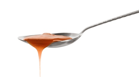 Tasty caramel sauce pouring from spoon isolated on white