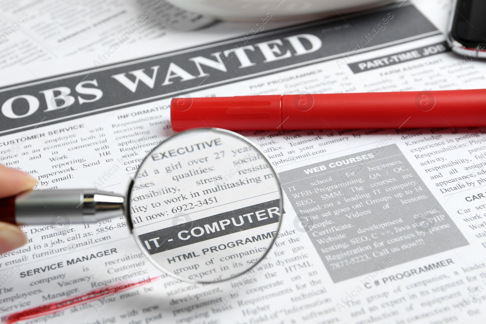 Photo of Looking through magnifying glass at newspaper, closeup. Job search concept