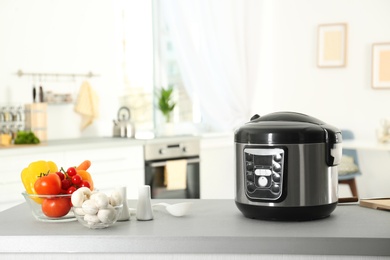 Photo of Modern multi cooker and products on table in kitchen