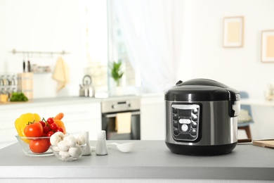 Modern multi cooker and products on table in kitchen