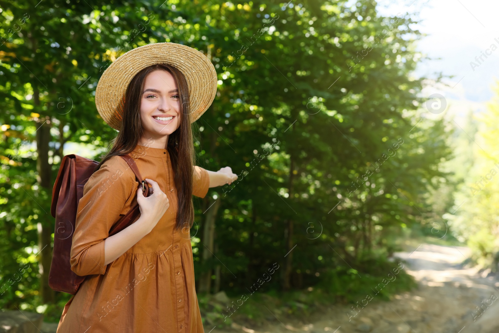 Photo of Happy woman with backpack and hat enjoying her walk in forest