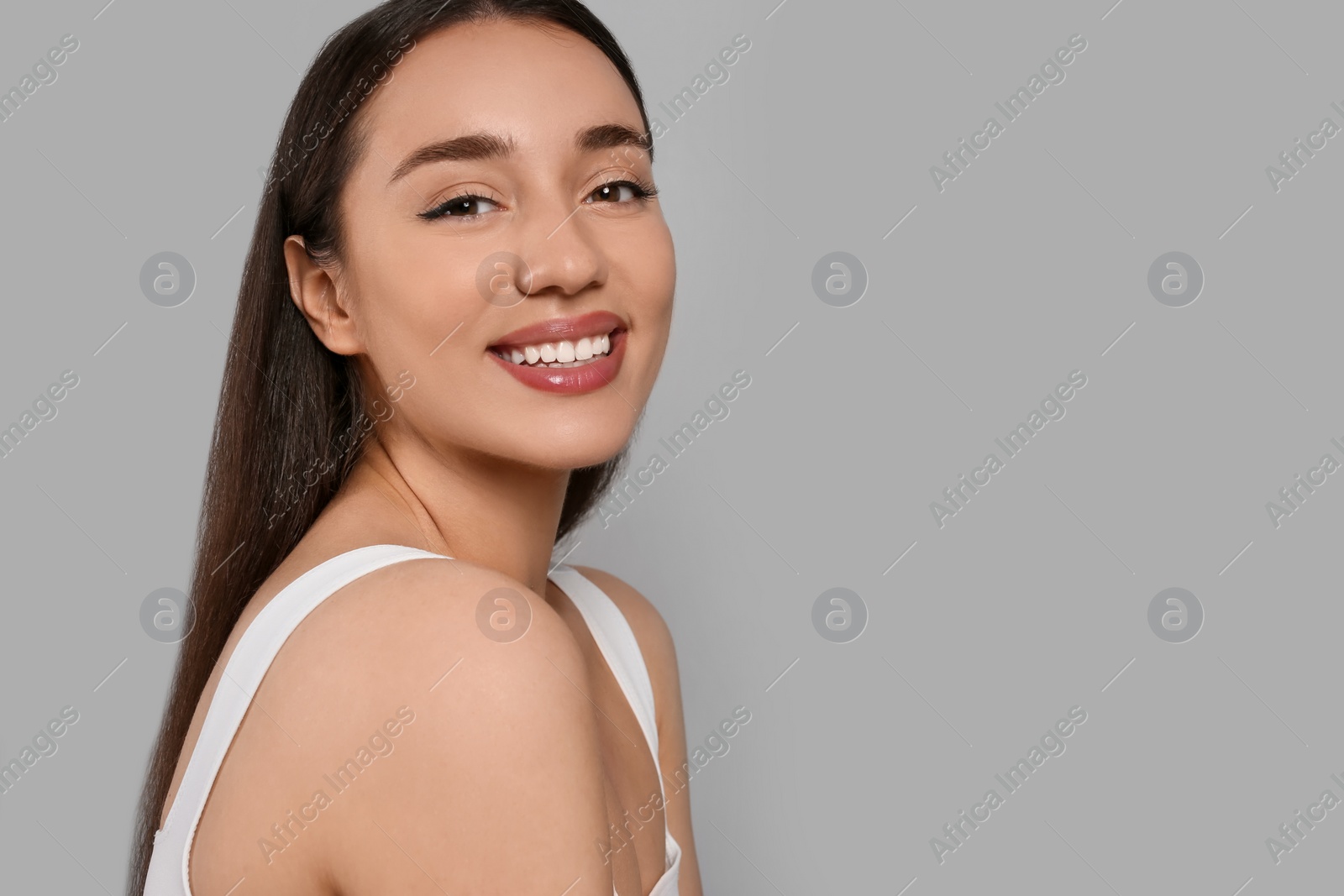 Photo of Portrait of beautiful young woman with elegant makeup on grey background. Space for text