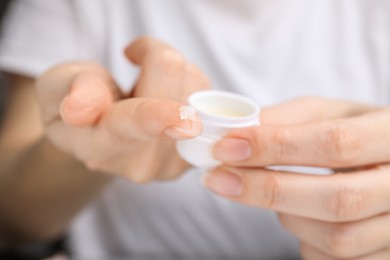 Photo of Woman taking cosmetic petrolatum from jar, closeup