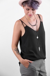 Trendy young woman with tattoo on white background